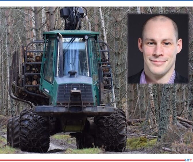 Smiling man on a background of a large tractor in the forest