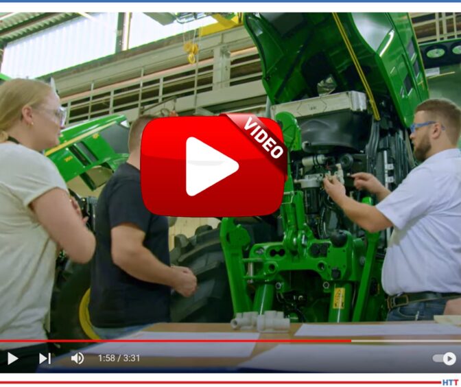 Group of three gathered around a John Deere tractor