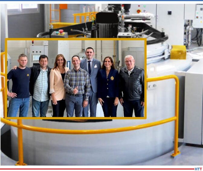 Smiling group of people to the forefront of a large pit furnace