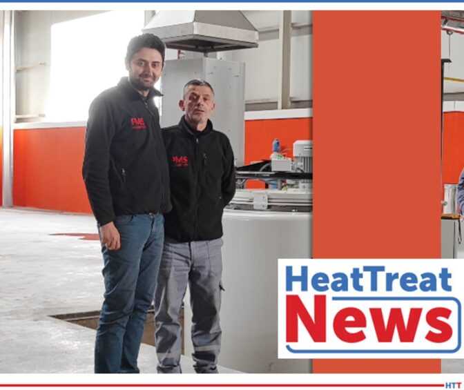 2 smiling men standing next to a white furnace with the words “heat treat news” overlayed on picture