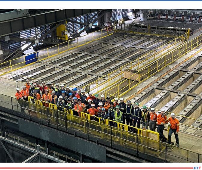 company members grouped in the foreground of a large, shop floor